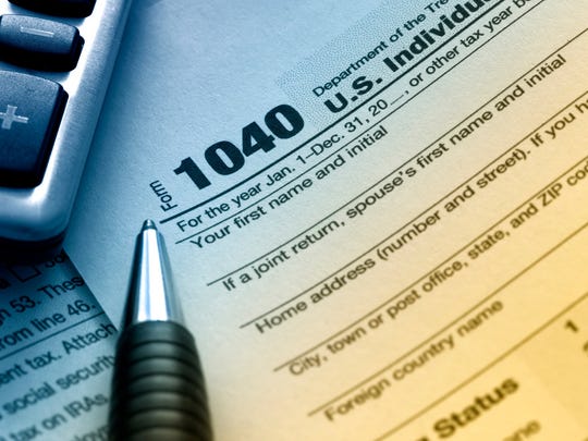 A 1040 tax return with a pen and calculator in view