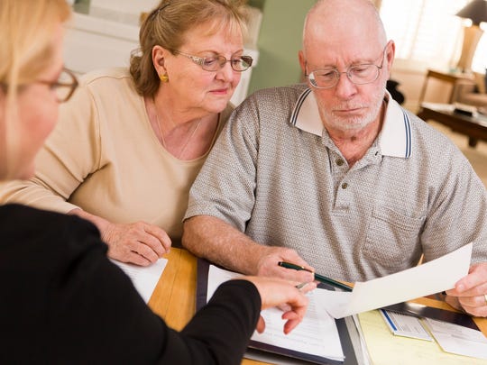 Older couple reviewing financial paperwork with advisor.