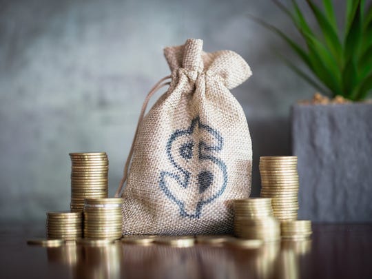 A bag with a dollar sign on it surrounded by gold coins.