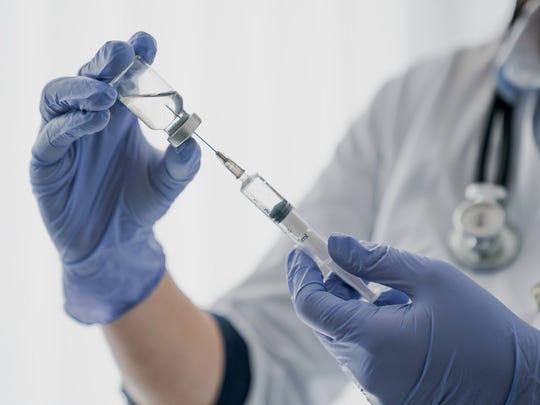 Healthcare worker holding a syringe with needle and a vaccine vial