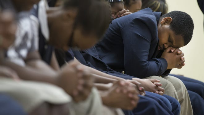 Students pray during chapel service in the new gymnasium at Hope Prima school in Milwaukee on Friday.