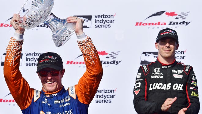 Scott Dixon, left, hoists the trophy after winning an IndyCar auto race as third-place finisher Robert Wickens applauds in Toronto, Sunday, July 15, 2018. (Frank Gunn/The Canadian Press via AP)