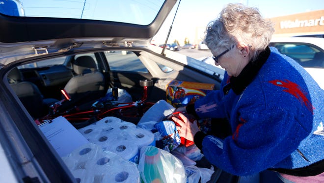 Judy Hellam load gifts into the back of a car after shopping for Share Your Christmas at Walmart.