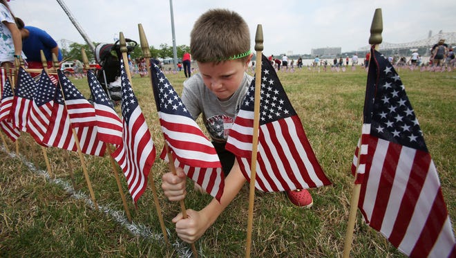 Blane Torzewski, 8, puts a little muscle into it as he plants on flag on the Great Lawn at Waterfront Park during the Flags4Vets event ahead of Memorial Day. May 27, 2017