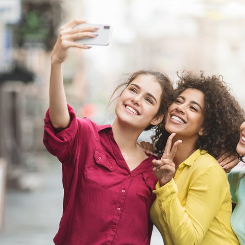 Three friends taking a smiling selfie with a smart