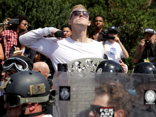 A man makes a slashing motion across his throat toward counter-protesters as he marches with other white nationalists, neo-Nazis and members of the "alt-right" during the "Unite the Right" rally Aug 12, 2017 in Charlottesville, Va.