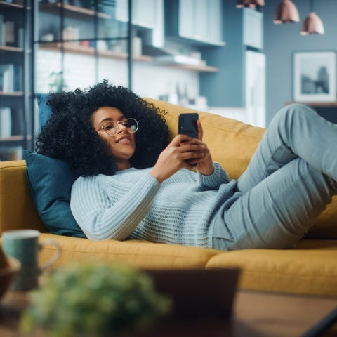 Person lying on couch using smartphone.