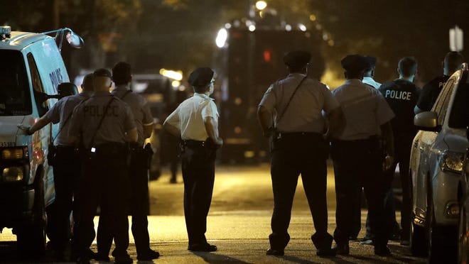 Policer officers watch as a gunman is apprehended following a standoff Wednesday, Aug. 14, 2019, in Philadelphia. A gunman who opened fire on police Wednesday as they were serving a drug warrant in Philadelphia, wounding several officers and triggering a standoff that extended into the night, is in police custody, authorities said. (AP Photo/Matt Rourke)