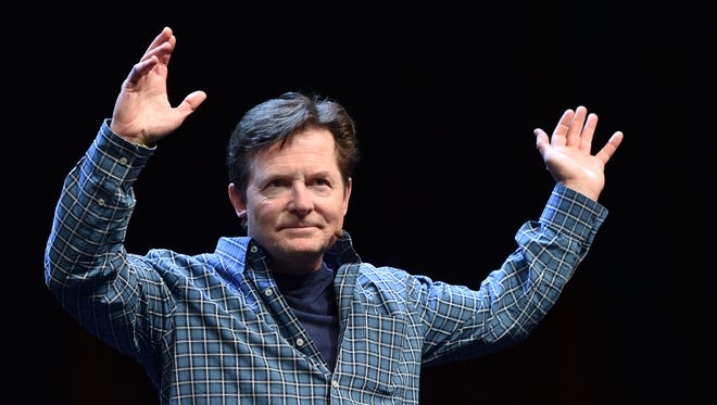 Michael J. Fox waves to a cheering crowd before a panel discussion on "Back to the Future" during the Silicon Valley Comic Con in San Jose on March 19, 2016.