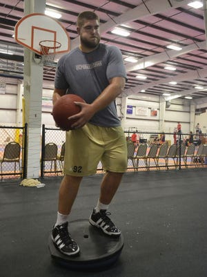 Drew Nowak keeps his balance while lifting a 15-pound medicine ball in an agility drill during a workout at House of Speed training facility in Ashwaubenon.
