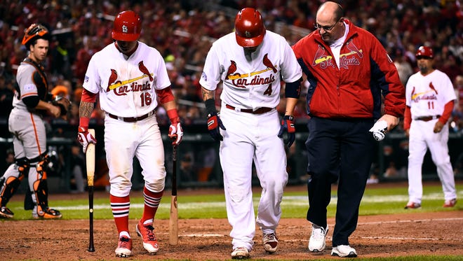 Cardinals catcher Yadier Molina (middle) is helped off the field by second baseman Kolten Wong (left) and a trainer after an apparent injury Sunday.