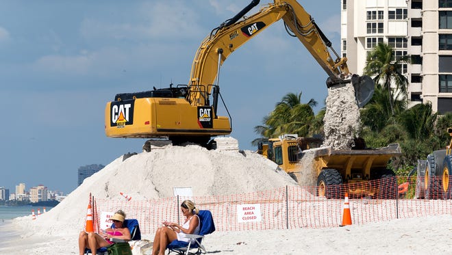 An excavator moves sand around on Park Shore Beach during a Collier County beach renourishment project using dump trucks on Wednesday, Nov. 2, 2016. 