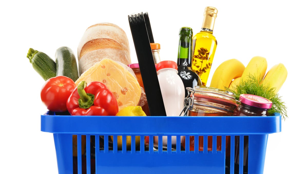 Shopping basket with variety of grocery products isolated on white