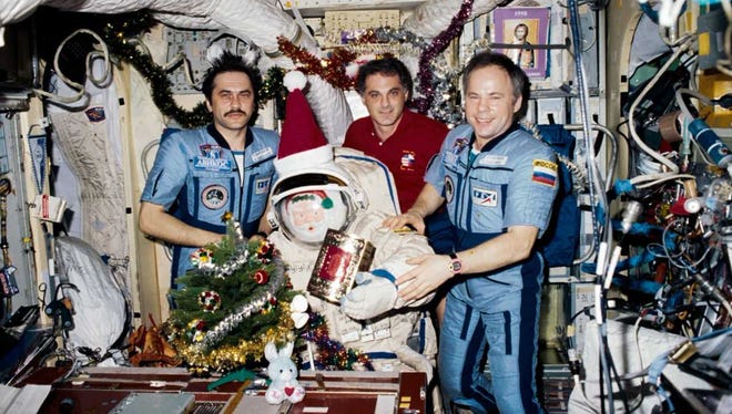 Mir Space Station crew members Pavel Vinogradov, David Wolf and Anatoly Solovyev pose with Santa in his Orlan space suit during Christmas 1997.