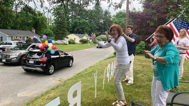 Sarah Cammarata, far right, waves to well-wishers during a drive-by 101st birthday celebration for her, joined by her daughter, Roseann Shorette, middle, and other family members.
