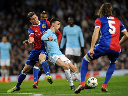 Basel's Fabian Frei, left, challenges for the ball with Manchester City's Phil Foden, center, during the Champions League, round of 16, second leg soccer match between Manchester City and Basel at the Etihad Stadium in Manchester, England, Wednesday, March 7, 2018. (AP Photo/Rui Vieira)
