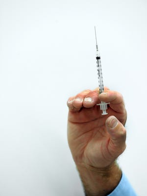 A pharmacist readies a flu shot.