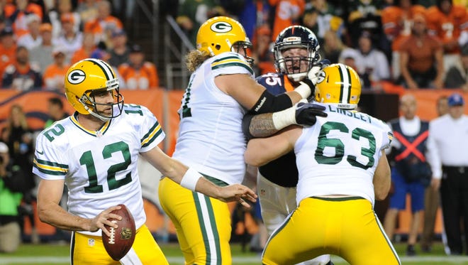Green Bay Packers quarterback Aaron Rodgers (12) scrambles as guard Josh Sitton (71) and center Corey Linsley (63) block against the Denver Broncos at Sports Authority Field.