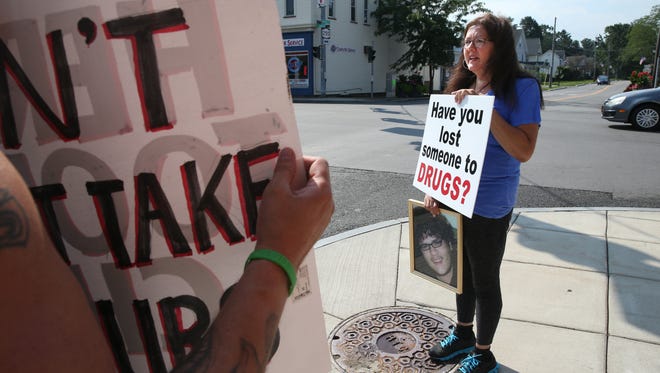 File photo: Cathy Warren of Webster stands at the four corners in the heart of Webster, where Main Street meets Route 250, and holds a sign to bring awareness to drug addiction and overdose deaths, Friday, Aug. 4, 2017.  Warren's son Curtis died May 19, 2015, of a drug overdose.  Standing with her are other local parents and grandparents who have also lost a loved one to drug addiction.