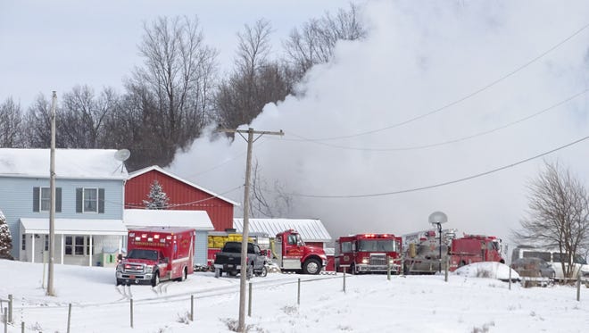 Fire trucks sit along an Ontario driveway Tuesday morning as smoke rises from a barn.