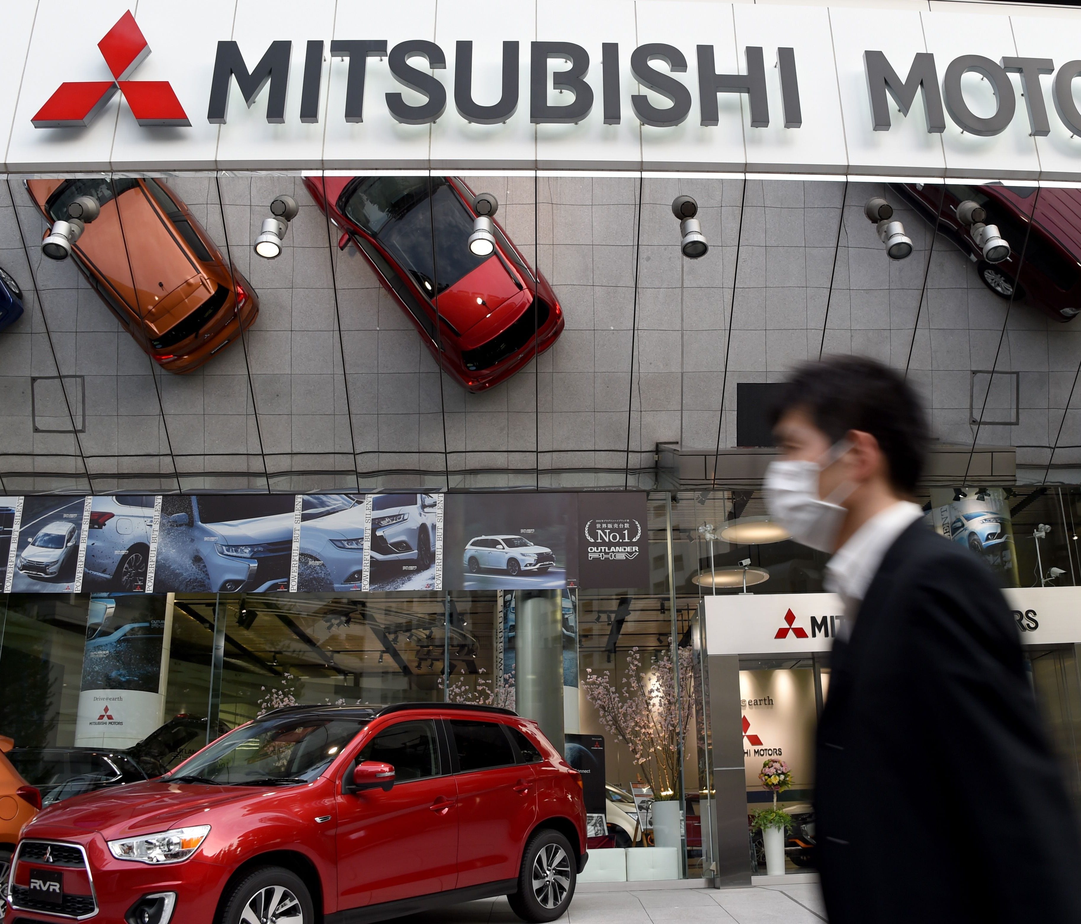 A businessman walks past Mitsubishi Motors headquarters in Tokyo.