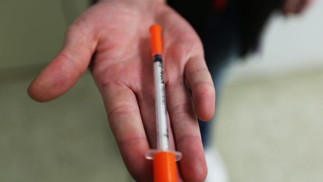 A heroin user holds a used syringe she brought to a needle exchange in Portsmouth, Ohio.