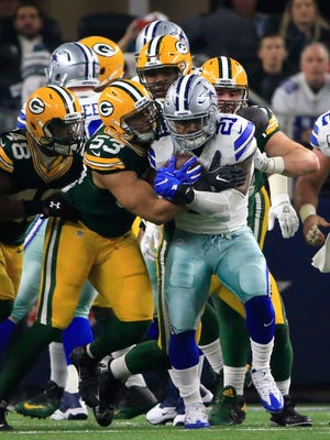 Cowboys running back Ezekiel Elliott (21) is wrapped up by Packers outside linebacker Nick Perry (53) during the second half of an NFL divisional playoff football game on Jan. 15 in Arlington, Texas.