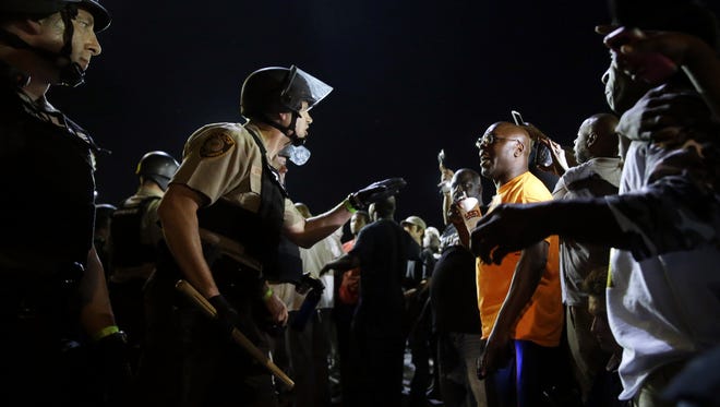In this Aug. 10, 2015, file photo, officers and protesters face off along West Florissant Avenue, in Ferguson, Mo. A federal judge will get an update Tuesday, Dec. 12, 2017, on progress the city of Ferguson is making in addressing concerns about mistreatment of black residents by the Missouri town's police and court system.