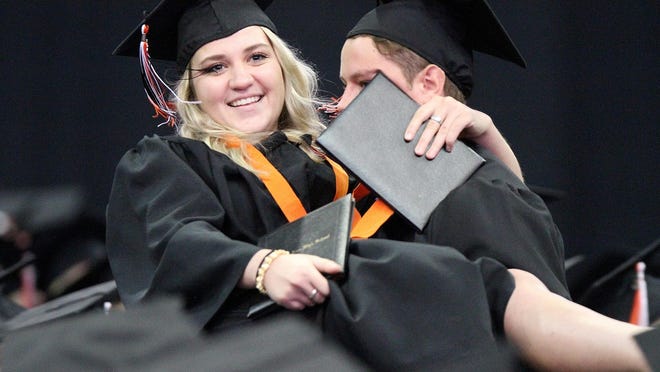 After collecting their diplomas, Joshua Springer, right, picks up his sister Hannah Springer, then carries her back to their seats as the Brighton 2015 Commencement draws to a close.