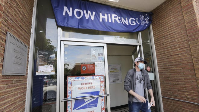 In this June 4, 2020, file photo, a customer walks out of a U.S. Post Office branch and under a banner advertising a job opening, in Seattle. The U.S. government will issue its latest snapshot Thursday, June 18, of the layoffs that have left millions unemployed but have slowed as businesses have increasingly reopened and rehired some of their laid-off workers.