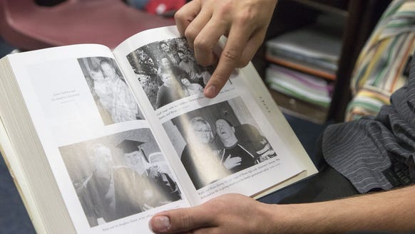 Tyler DeMoe points to photographs in a book that includes