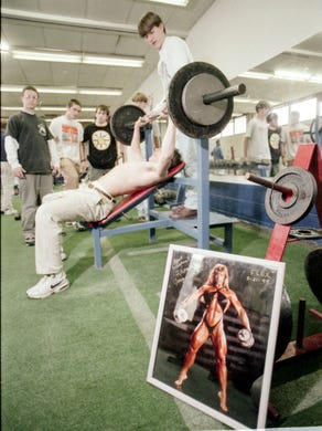 The West High School soccer team, from left, Brian Maddox, Jon Magnuson, Brian Tapp, and Robert McKeehan watch as Johnny Adams spots for Erik Gast, work, out in the weight room with a framed photograph of body builder Rhonda Jorgenson in March 1996.
