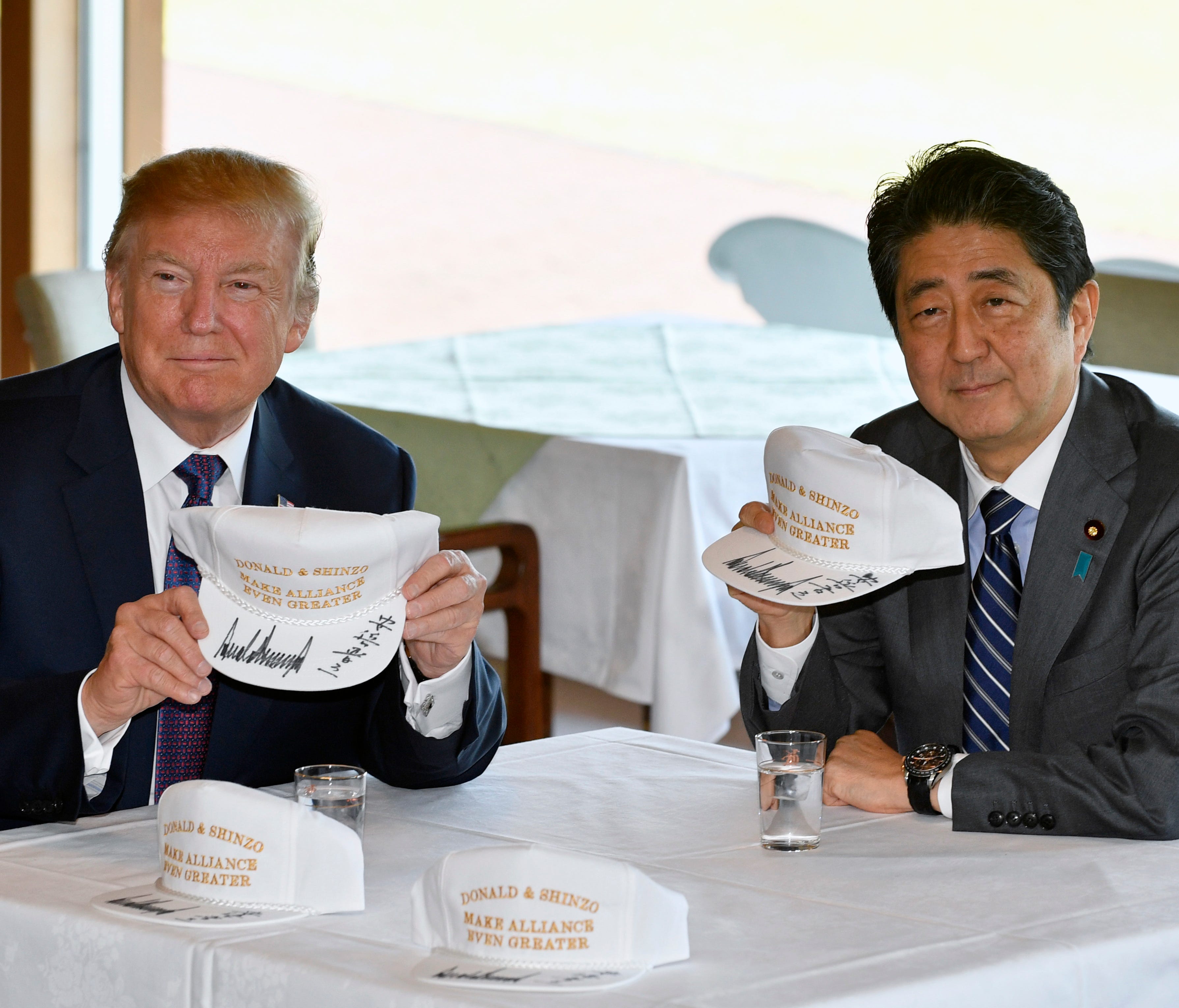 President Trump and Japanese Prime Minister Shinzo Abe pose after they signed hats reading 