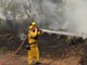 A firefighter hoses down the area around a burning