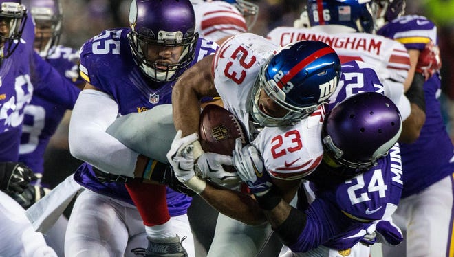 Giants running back Rashad Jennings is tackled by Minnesota Vikings cornerback Captain Munnerlyn (right) and linebacker Anthony Barr during the second quarter of Sunday night’s game in Minneapolis.
