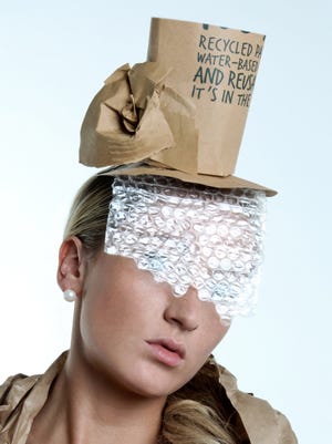 Woman wearing recycled paper hat with bubble wrap veil covering her face