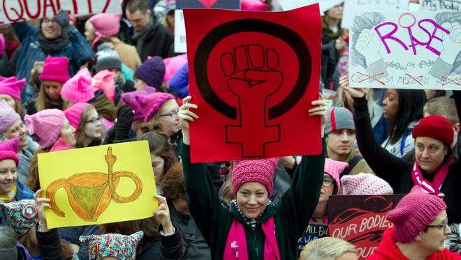Women with bright pink hats and signs gather early and are set to make their voices heard on the first full day of Donald Trump's presidency, Saturday, Jan. 21, 2017 in Washington.