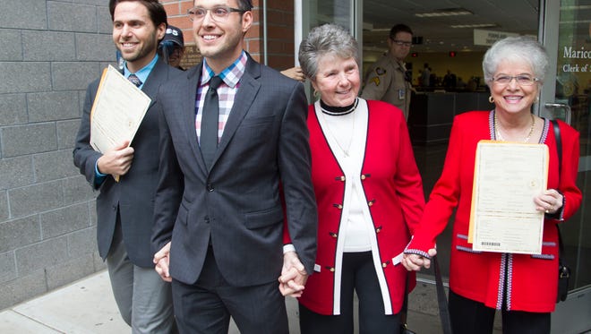 The first two couples to receive marriage licenses minutes after gay marriage was legalized in Arizona come out of the Clerk of the Superior Court all smiles in Phoenix, Friday, October 17, 2014. From left to right are; David Larance, 36, Kevin Patterson, 31, both Phoenix, and Nelda Majors, 76, and Karen Bailey, 75, both Scottsdale.