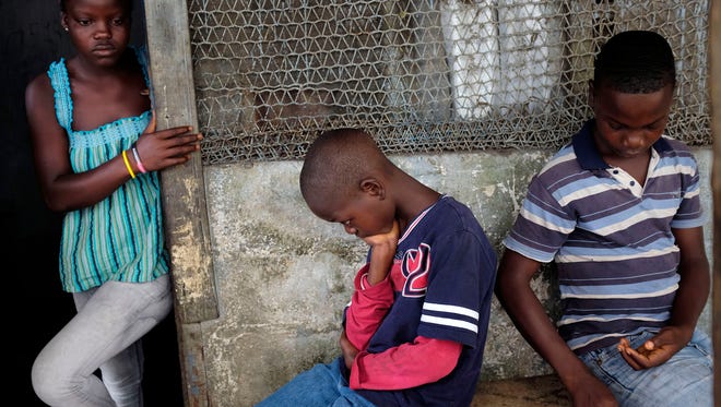 The orphaned Cooper children -- Promise, 16, Emmanuel Junio, 11, and Benson, 15, sit at their St. Paul Bridge home in Monrovia, Liberia.
