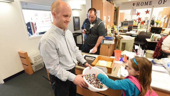 Zane Grey Elementary School assistant principal Michael Emmert hands out Devil Dollars rewards to students on Friday. Emmert was named Outstanding Assistant Principal by the Ohio Association of Elementary School Administrators.