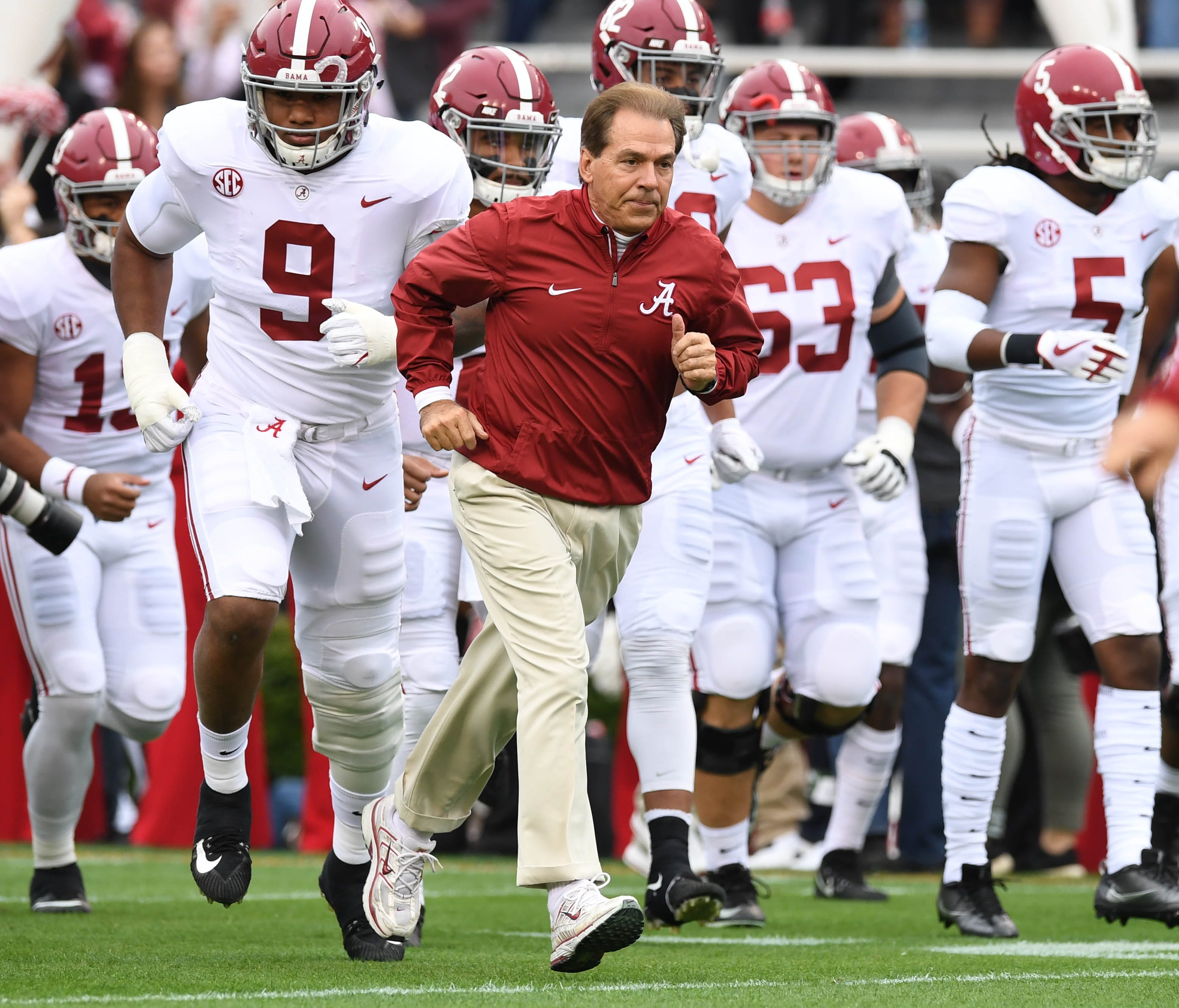 Alabama coach Nick Saban runs on the field with his players before their game against Auburn.