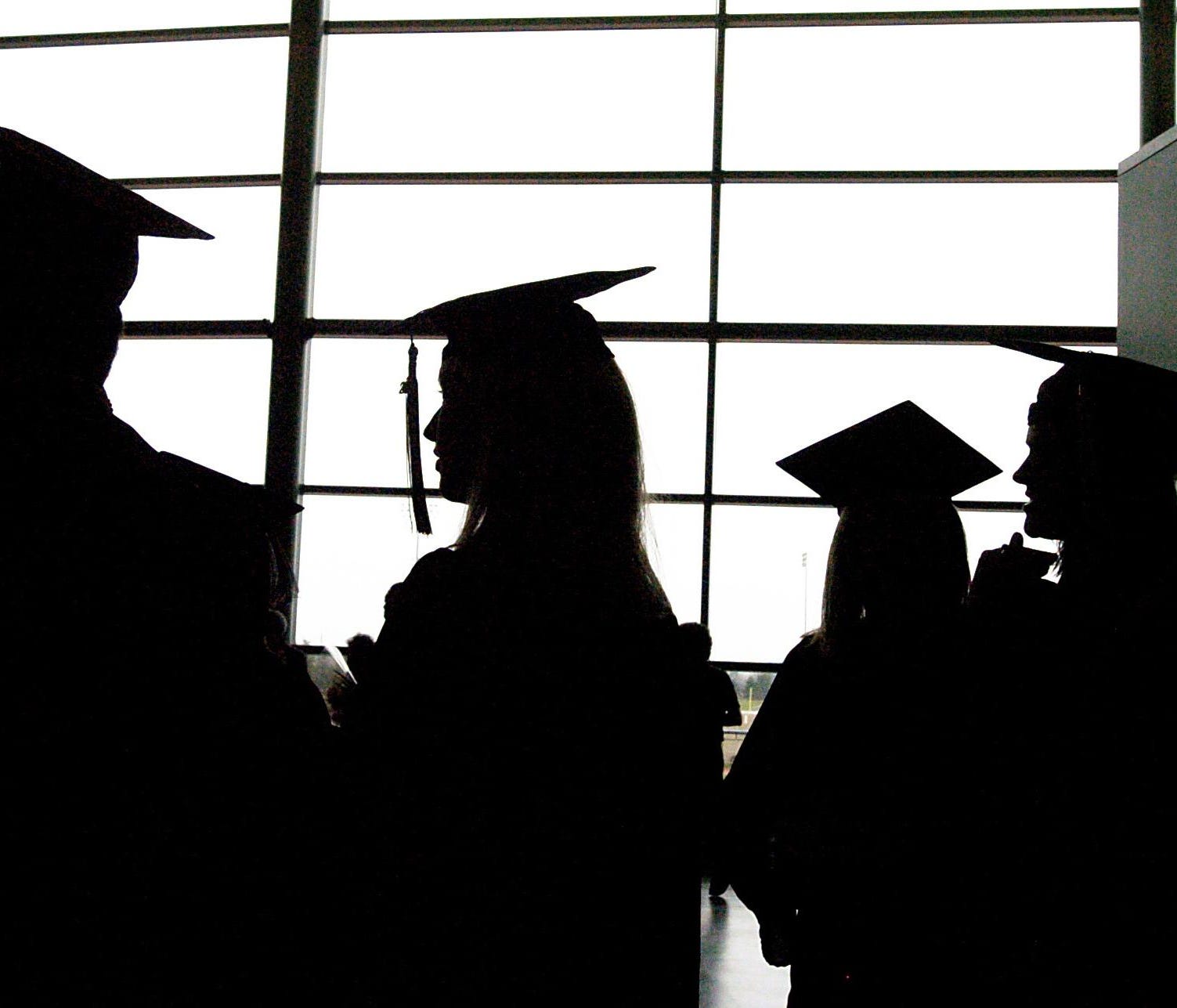 FILE - In this Sunday, Dec. 17, 2006, file photo, Eastern Michigan University graduates socialize before their commencement at the Convocation Center in Ypsilanti, Mich. In recent years, the Consumer Financial Protection Bureau and the Federal Trade 