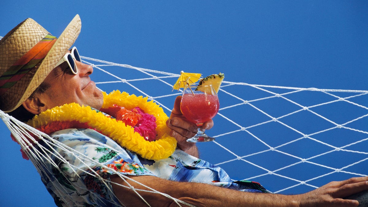 Mature man sitting in hammock with drink in hand