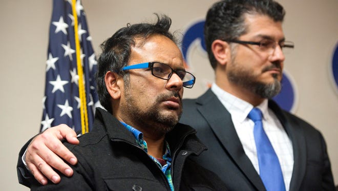 Farhan Khan, left, brother-in-law of one of the suspects involved in a shooting in San Bernardino, Calif., is held by Hussam Ayloush, executive director of Council on American-Islamic Relations, during a news conference