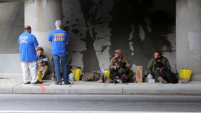 Workers from Lighthouse Youth Services talk to homeless people and their dogs under an underpass at Clifton and Spring Grove Avenues.