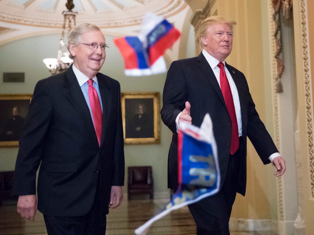 Small Russian flags bearing the word 'Trump' are thrown by a protester toward President Trump, as he walks with Senate Majority Leader Mitch McConnell, R-Ky., on Capitol Hill on Oct. 24, 2017, to have lunch with Senate Republicans and push for his ta