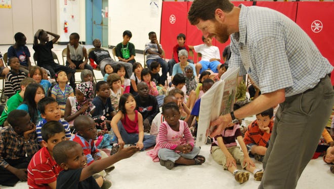 Children's Literacy Foundation Executive Director Duncan McDougall reads stories and helps students find books to take home at The Integrated Arts Academy at H.O. Wheeler School in Burlington in this 2010 photo.