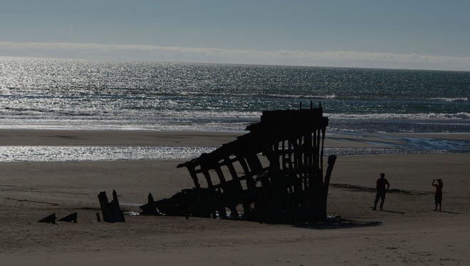 Visitors explore the rusty remains of the century-old shipwreck Peter Iredale along the beach at Fort Stevens State Park near Astoria on Saturday, July 26, 2014.