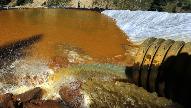 In this Aug. 14, 2015 photo, water flows through a series of sediment retention ponds built to reduce heavy metal and chemical contaminants from the Gold King Mine wastewater accident, in the spillway about a quarter mile downstream from the mine outside Silverton, Colo. A year after a mine waste spill, residents are taking a break from the aftermath for a party that includes a specially brewed beer the color of the spill. They're also taking a few jabs at the federal Environmental Protection Agency, which accidentally caused the 3-million-gallon spill at the Gold King Mine on Aug. 5, 2015.