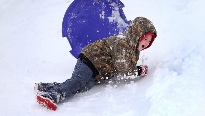Tyler Moreifled has a minor spill in the snow while sledding with his family at Garfield Park Sunday morning following the heavy snowfall over night in the central Indiana area.